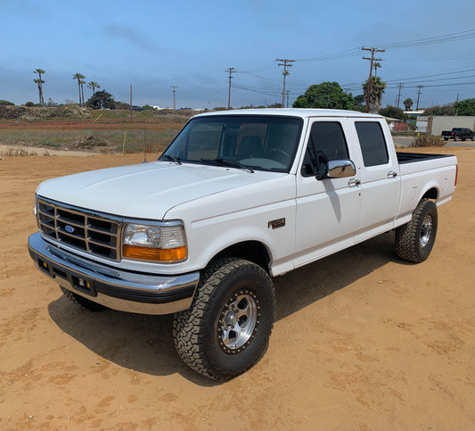 White pickup truck on a dirt road with a clear sky