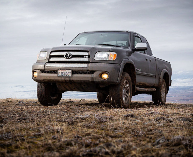 Gray Toyota truck parked on a grassy field with a cloudy sky.