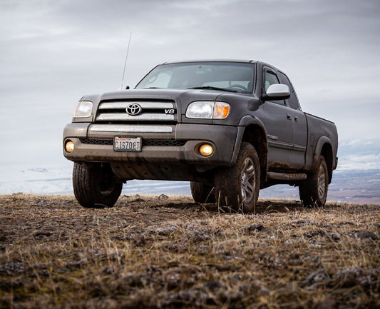 Gray Toyota truck parked on a grassy field with a cloudy sky.